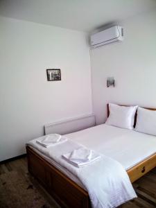 um pequeno quarto com uma cama com lençóis brancos em Guesthouse White Margarit em Melnik