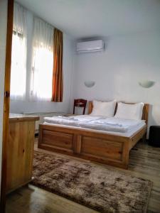 1 dormitorio con 1 cama grande de madera en una habitación en Guesthouse White Margarit en Melnik
