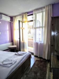a bedroom with a bed and a large window at Guesthouse White Margarit in Melnik