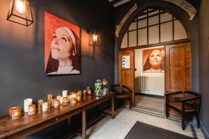 Cette chambre comprend une table avec des bougies et des portraits sur le mur. dans l'établissement Hotel Monasterium PoortAckere Ghent, à Gand