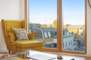 uma sala de estar com uma cadeira e uma grande janela em 1 Bedroom Stylish Apartment near Regents Park FREE WIFI & AIRCON by City Stay Aparts London em Londres