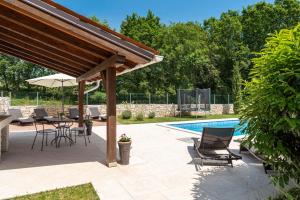 a patio with a table and chairs next to a pool at Villa Natasha - charming Istrian villa with private heated pool in Ružići