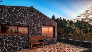 un edificio in pietra con una panchina all'esterno di sunset and stars stone house a Garafía