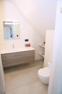 ein weißes Bad mit einem WC und einem Waschbecken in der Unterkunft B&B Intermezzo in Middelkerke