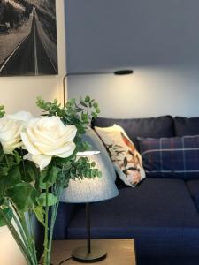 ein Wohnzimmer mit einem blauen Sofa und einer Vase aus Blumen in der Unterkunft LLN lodge in Louvain-la-Neuve