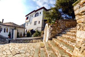 a white house with a stone wall and a building at Hotel Adam in Makrinitsa