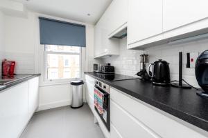 een keuken met witte kasten en zwarte aanrechtbladen bij Gorgeous Apartment by Hyde Park (SS4) in Londen