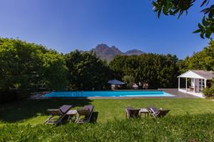 a swimming pool with chairs and a table in the grass at Kronendal Heritage in Hout Bay