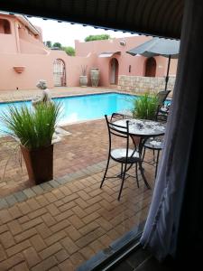 a patio with a table and chairs next to a pool at El Gran Chaparral Guest House in Pretoria