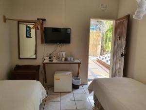 a room with two beds and a desk and a television at A Traveller's Palm in Phalaborwa