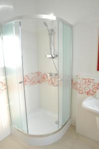 La salle de bains est pourvue d'une douche avec une porte en verre. dans l'établissement Piros Arany Panzió Kalocsa, à Kalocsa