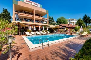 a hotel with a swimming pool in front of a building at Hotel Capri in Nesebar