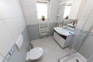 a white bathroom with a toilet and a sink at Hotel Heritage in Tirana