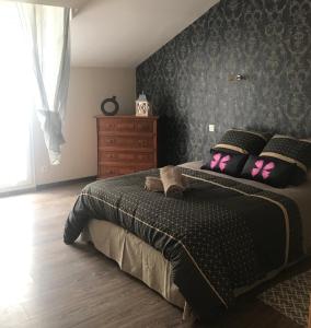 een slaapkamer met een bed met roze vlinderkussens bij l appart de Lilly in Pierry