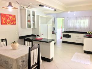 una cocina con armarios blancos y una mesa con comedor. en Casa Barra da Lagoa, 20 metros da praia LAG163, en Florianópolis