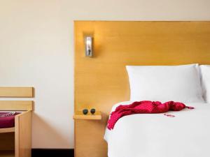 a bed with a white comforter and pillows at ibis Muscat in Muscat