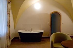 uma casa de banho com uma banheira e uma cadeira em Penzion Zlatý vůl em Znojmo