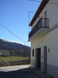 a white building with a balcony on the side of it at La Fuente de la Covatilla in La Hoya