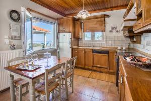 Una cocina con gabinetes de madera y una mesa con sillas. en Vista Del Mare Luxury Villa, en Koinira
