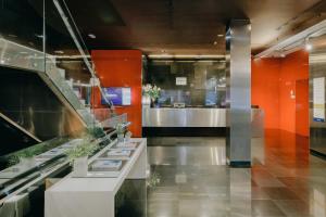 a lobby with orange walls and a counter with plants at Hesperia Bilbao in Bilbao
