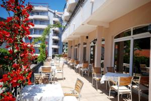 eine Reihe von Tischen und Stühlen auf einer Terrasse mit roten Blumen in der Unterkunft Hotel Magnolija in Budva