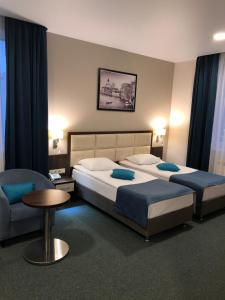 een slaapkamer met 2 bedden, een stoel en een tafel bij Iskra Hotel in Chimki