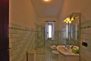 y baño con 2 aseos, lavamanos y ducha. en Villa Arancio, en Cala Liberotto