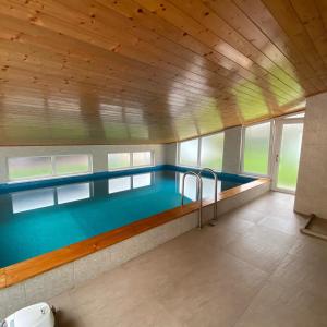 a swimming pool in a building with a wooden ceiling at Penzion Pod Zámkem in Pruhonice