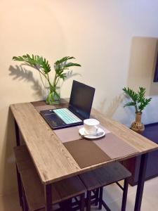 a laptop computer on a wooden table with a cup of coffee at Cozy studio in Cebu IT Park in Cebu City