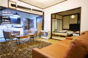 uma sala de estar com um sofá e uma televisão em 札幌ドーム前ハウス Sapporodome front house em Sapporo