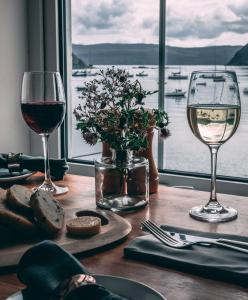 ポートリーにあるThe Rosedale Hotel & Restaurantの水辺の景色を望むテーブルの上にワイン2杯