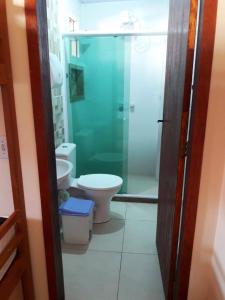 a bathroom with a toilet and a glass shower at Hospedagem Caravela in Arraial do Cabo