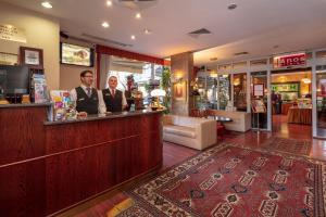 two men standing at a bar in a store at Hotel Charles in Budapest