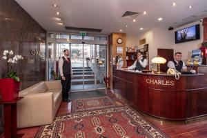 a man standing at a bar in a hotel lobby at Hotel Charles in Budapest