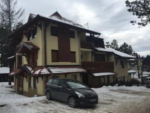 une voiture garée devant une maison dans la neige dans l'établissement Nena apartman, à Zlatibor