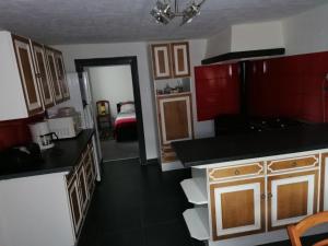 a kitchen with red cabinets and a room with a bed at Gite la Tourbiere in Fellering