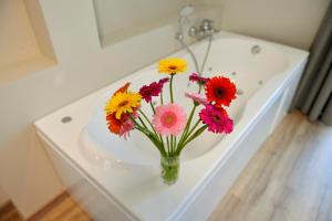 a white vase filled with pink flowers next to a bathroom sink at Du Parc Hotel in Sauze dʼOulx
