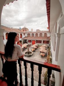 a woman standing on a balcony looking out at a courtyard at Hotel Santa Rosa in Ayacucho