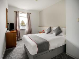 Un dormitorio con una cama grande y una ventana en OYO Glenpark Hotel, Ayr Central en Ayr