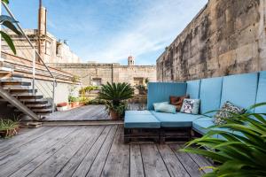 a patio with a blue couch on a wooden deck at Valletta Lucente Guest House in Valletta