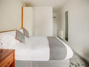OYO Glenpark Hotel, Ayr Central في آير: غرفة نوم مع سرير أبيض كبير وخزانة خشبية