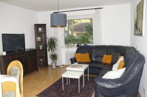 a living room with a black leather couch and a table at Ferienwohnung auf Resthof in Nordhorn