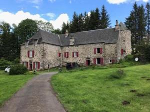 a large stone building with red windows on a field at Ferme des Prades in Landeyrat +26 photos