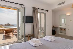 a bedroom with a bed and a view of the ocean at Trinity Mykonos - Villa & Beachfront Boutique Hotel in Platis Yialos Mykonos