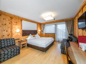 a hotel room with a bed and a couch at Hotel Alaska in Selva di Val Gardena
