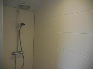 een douche met een douchekop in de badkamer bij Vakantiewoning 't Steechje in Hollum