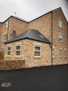 a brick building with a black roof at Fabulous One Bedroom Apartment in Ripon City Centre in Ripon