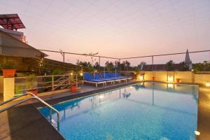 a pool on the roof of a building with blue chairs at Fort Abode in Cochin