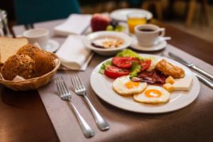 a table with a plate of eggs and vegetables and bread at New City Hotel & Restaurant Niš in Niš +41 photos