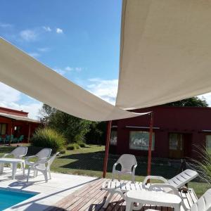 a group of chairs and a patio with a white umbrella at La Celina Casas de Campo in Nono